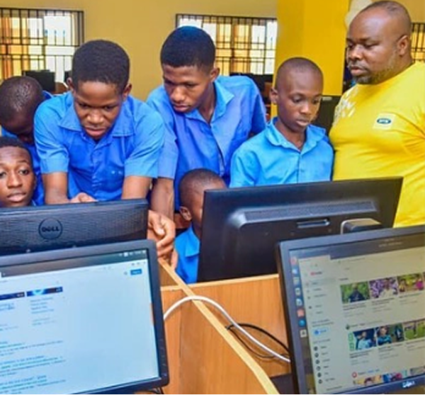 Students at computers in a school ICT lab with an MTN volunteer